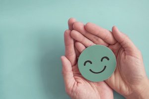 Hands holding green happy smile face paper cut, good feedback rating and positive customer review, experience, satisfaction survey ,mental health assessment, child wellness,world mental health day concept